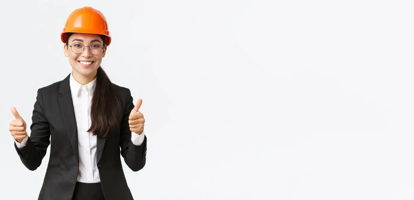 Ausgezeichnete Arbeit, gute Leistung: Zufriedene, professionelle Ingenieurin/Architektin im Bauwesen mit Schutzhelm und Anzug, die zustimmend den Daumen hochzeigt, wirbt für ein zum Verkauf stehendes Haus vor weißem Hintergrund.