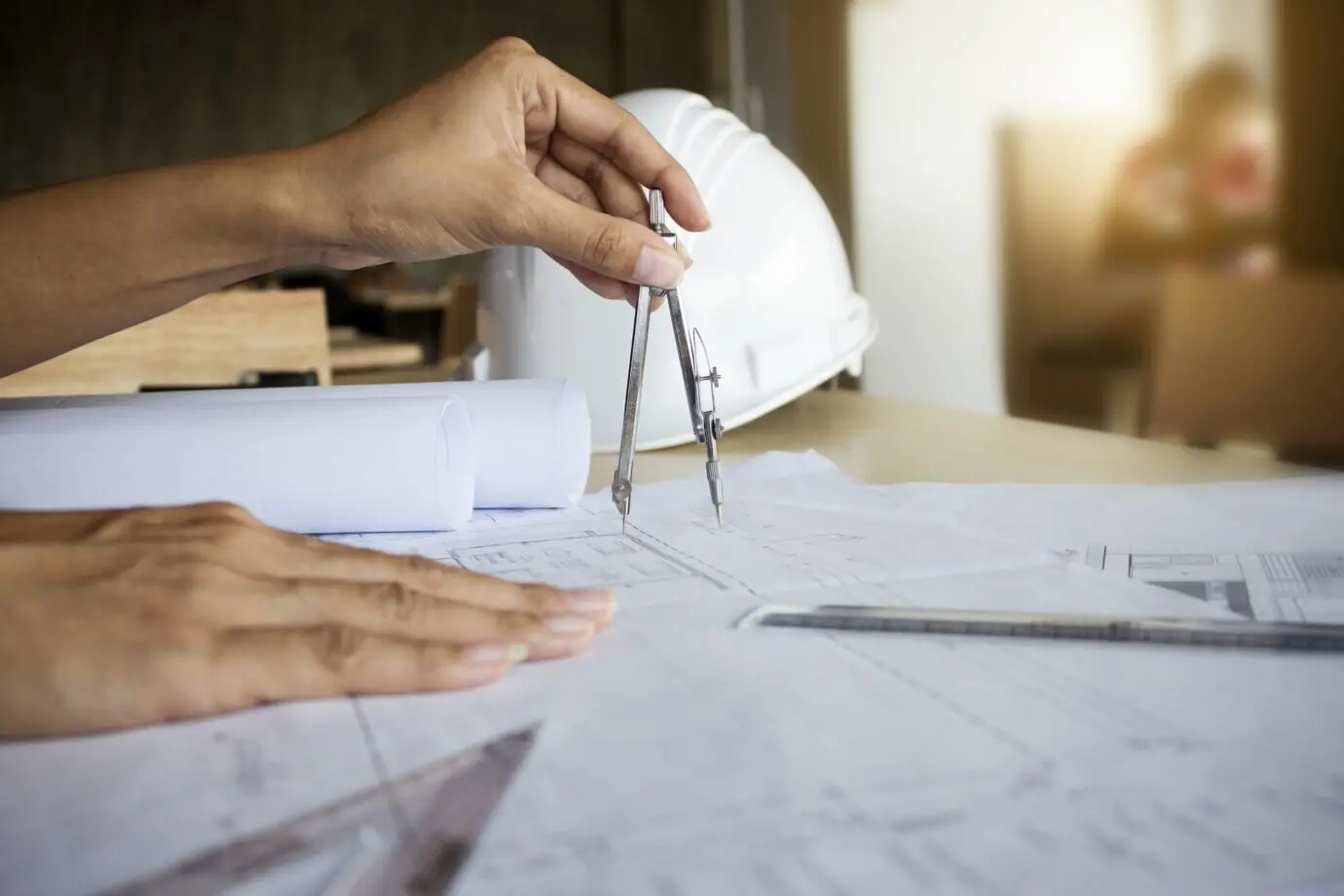 Hände eines Ingenieurs, der an einem Bauplan arbeitet; Baukonzept. Ingenieurwerkzeuge. Retro-Filter im Vintage-Ton, weiche Fokussierung (selektiver Fokus).